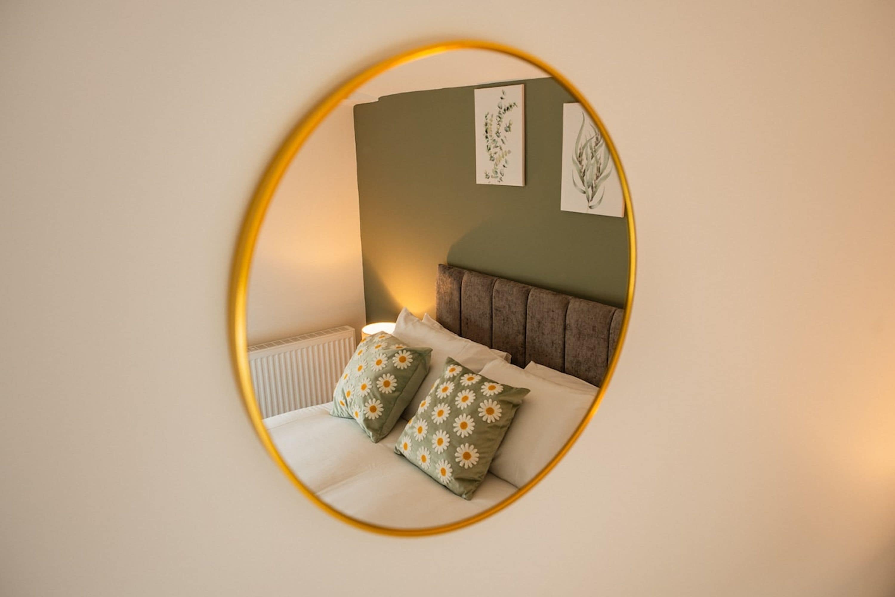 Ein Schlafzimmer mit einem Bett, zwei Kissen, einem Kopfteil und einer Wand mit zwei gerahmten Bildern.