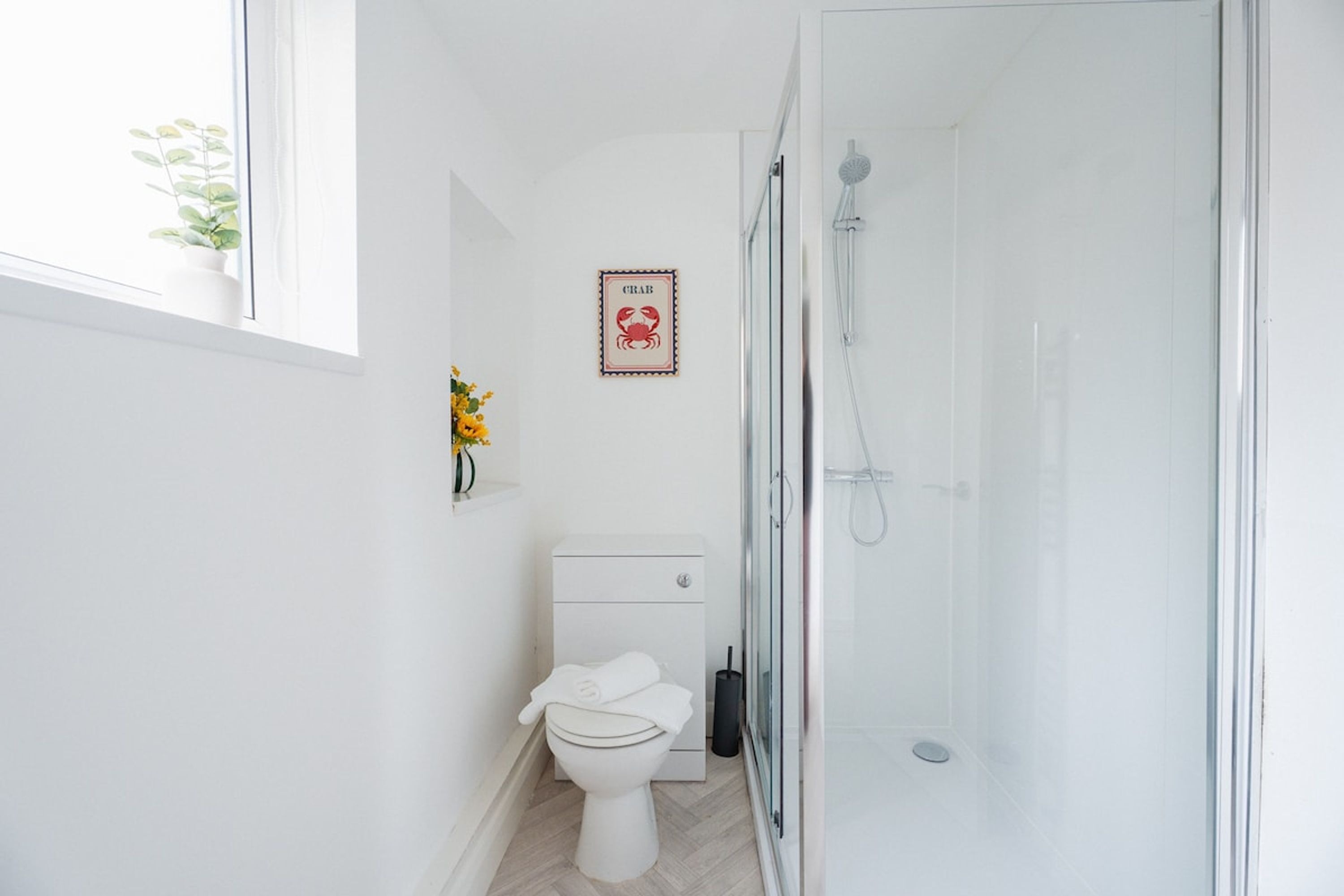 A modern bathroom with a toilet, a shower, and a framed picture on the wall.