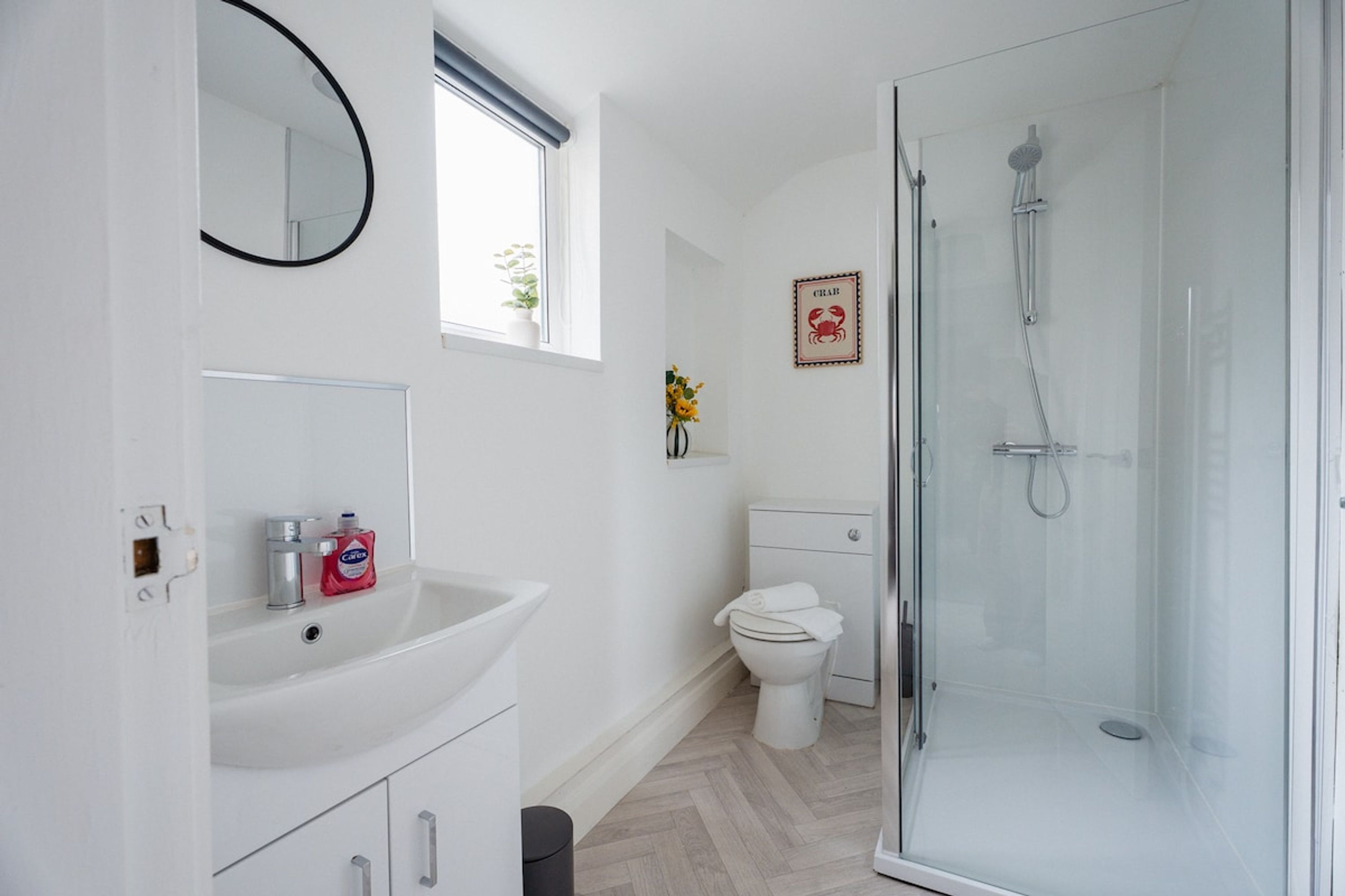 A modern bathroom with a glass shower enclosure, a white sink with a mirror, and a toilet.