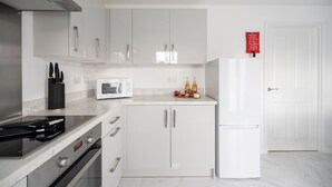 Eine moderne Küche mit weißen Schränken, einer Mikrowelle, einem Herd und einem Kühlschrank.