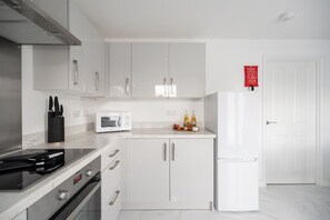 Eine moderne Küche mit weißen Schränken, einer Mikrowelle, einem Herd und einem Kühlschrank.