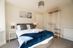 A bedroom with a bed, bedside tables, a wardrobe, and a painting on the wall. - Westbourne House Horizon Stays (Middlesbrough)