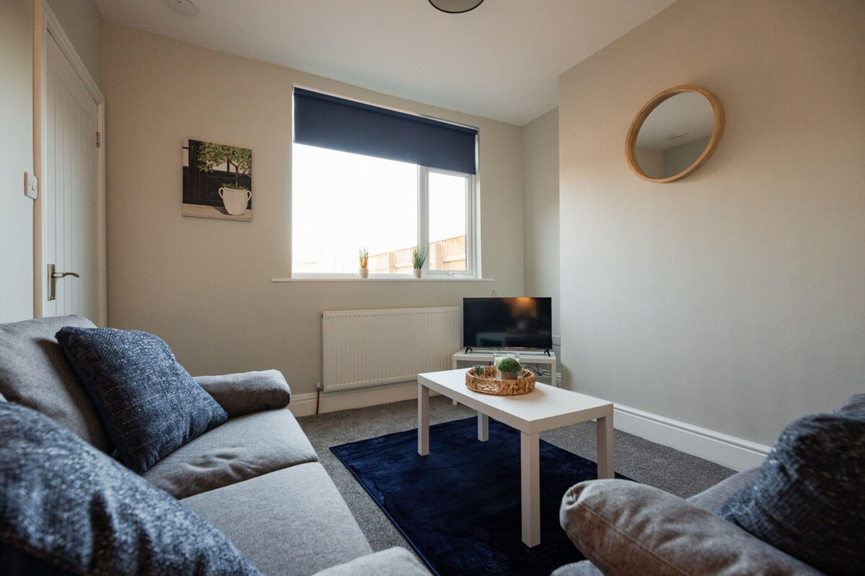 Una sala de estar con sofá, mesa de centro, televisor y ventana con vistas.