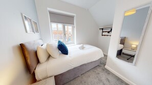 Ein Schlafzimmer mit Bett, Fenster, Spiegel und Blick ins Freie.