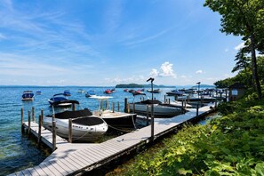 A marina with several boats docked at wooden piers, surrounded by greenery and a clear sky. - Gilford Lake Retreat • Minutes to Gunstock Mountain Ski Resort• 5-Min Walk to Beach • Pool (Gilford)