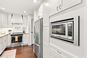 A modern kitchen with white cabinetry, stainless steel appliances, and a built-in microwave. - Gilford Lake Retreat • 5-Min Walk to Beach • Pool (Gilford)