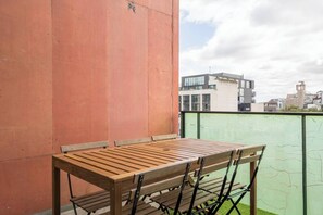 Ein Holztisch mit Stühlen auf einem Balkon mit Blick auf die Stadt.
