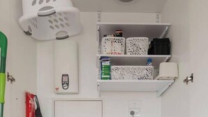 Un área de lavandería compacta con lavadora, un lavabo y estanterías.
