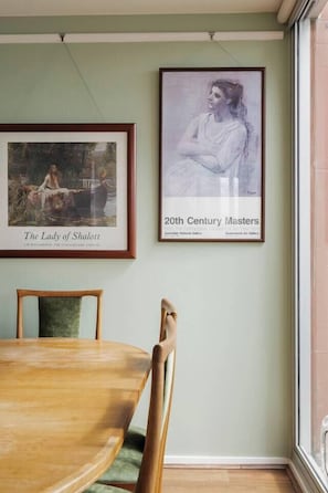 Ein Essbereich mit Holztisch und -stühlen, einem Kunstwerk an der Wand und einem Fenster mit Aussicht.