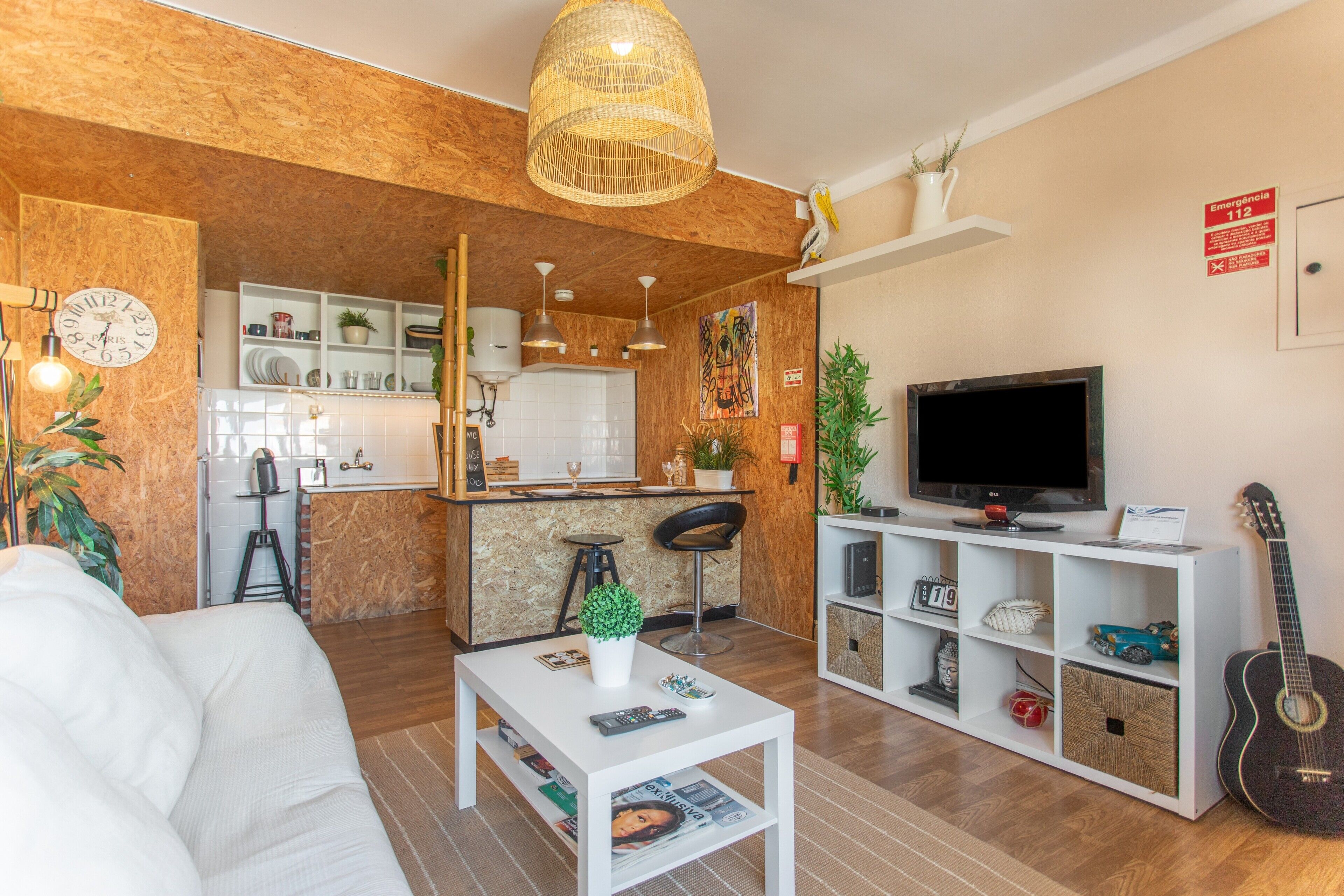 Uma sala de estar moderna com um sofá branco, uma mesa de centro, uma televisão e uma guitarra.