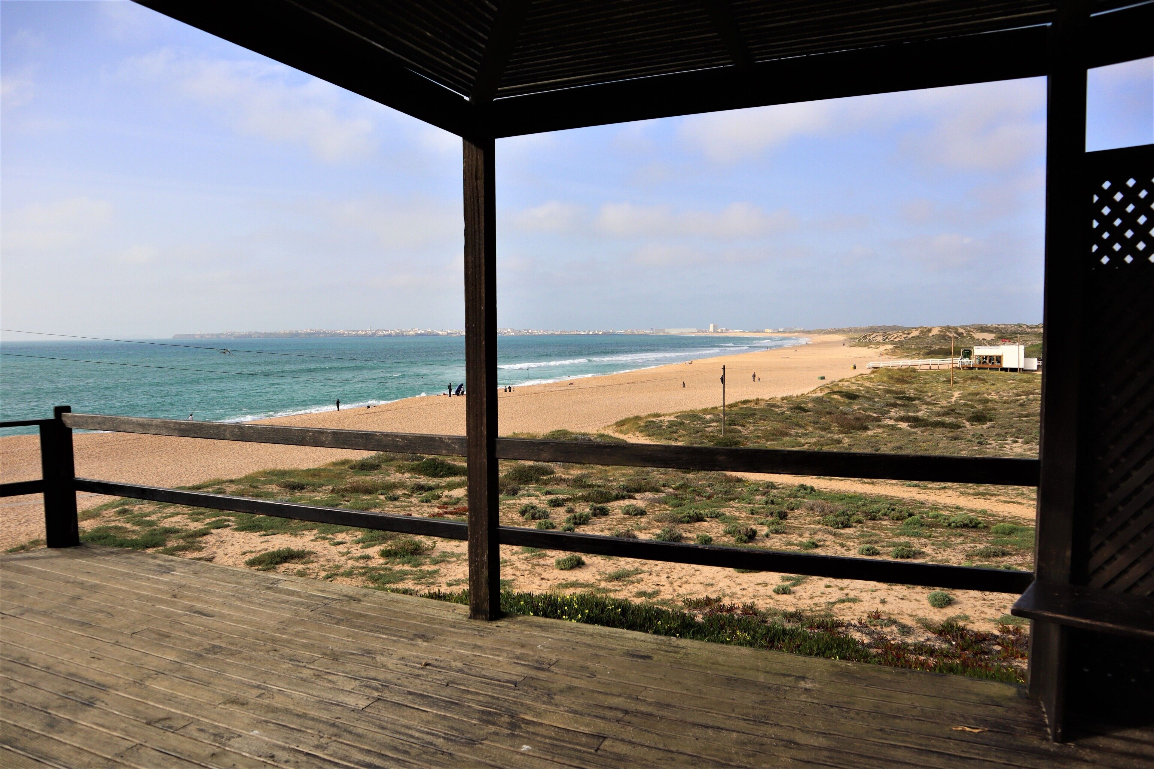 Une terrasse en bois offrant une vue sur une plage et l’océan.