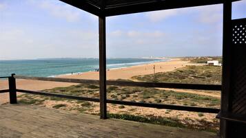 Une terrasse en bois offrant une vue sur une plage et l’océan.