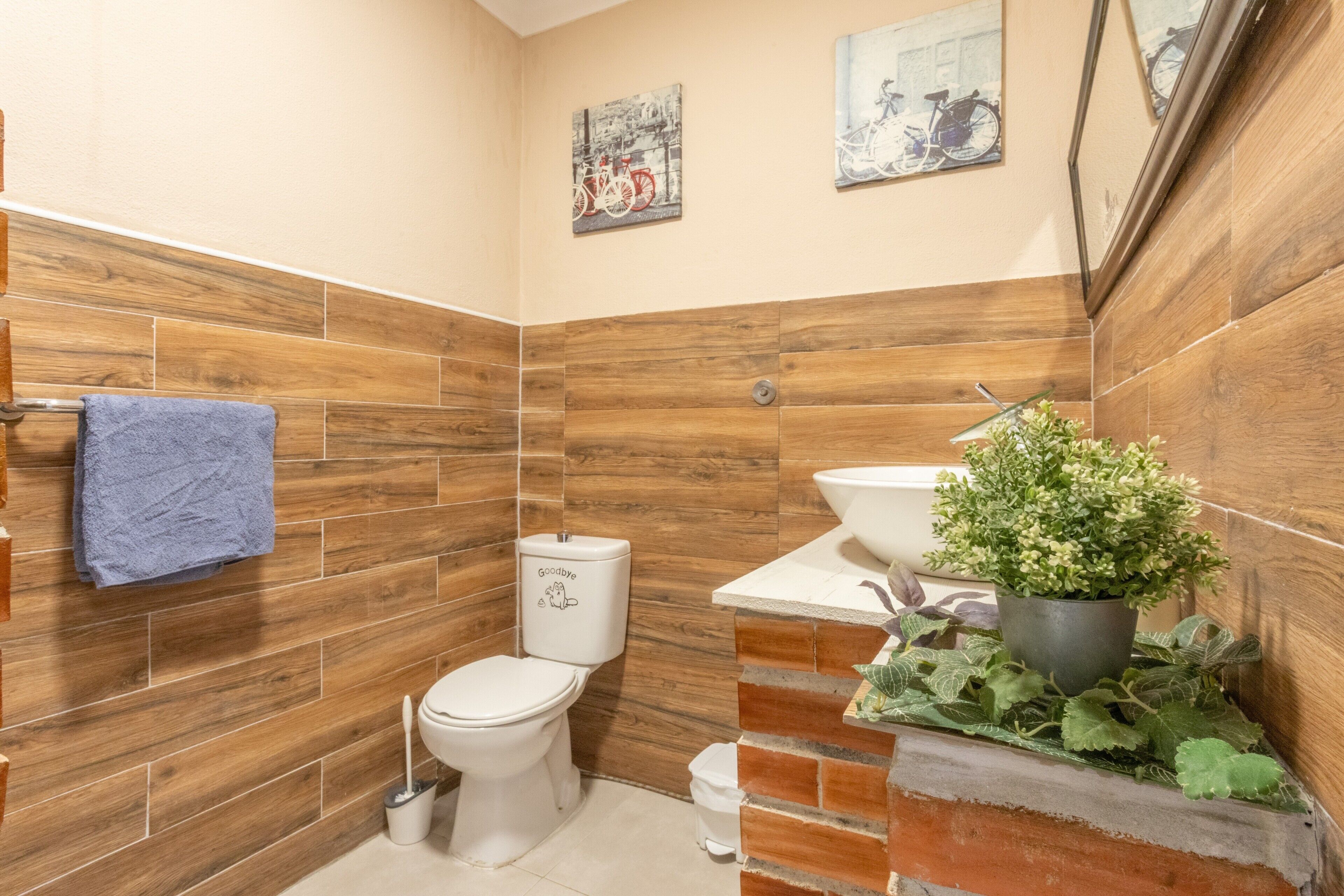 Ein Badezimmer mit Holzwandfliesen, einer Toilette, einem Waschbecken und einem blauen Handtuch.