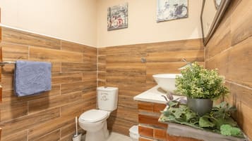 Ein Badezimmer mit Holzwandfliesen, einer Toilette, einem Waschbecken und einem blauen Handtuch.
