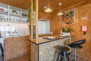 Una cocina con una isla de madera, taburetes de bar, una pizarra y una pared con grafitis coloridos.