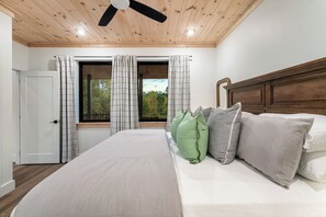 A bedroom with a bed, curtains, and a view through a window. - Modern Cabin | Near Dollywood | Hot tub | Arcade (Sevierville)