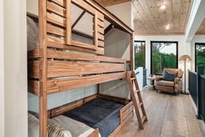 A bunk bed with a ladder, a sofa, and a table with a lamp in a room with large windows. - Modern Cabin | Near Dollywood | Hot tub | Arcade (Sevierville)