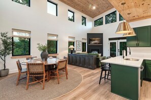 A spacious living area with a dining table, chairs, a fireplace, and a kitchen island. - Modern Cabin | Near Dollywood | Hot tub | Arcade (Sevierville)