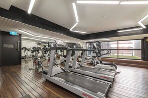 Ein Fitnessraum mit Laufbändern, Ergometer und einer Spiegelwand.