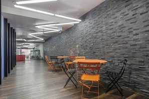 Ein modernes Interieur mit Backsteinwand, Holzboden und orangefarbenen Stühlen um einen Tisch.
