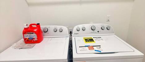 Two front-loading washing machines with a shelf above them.