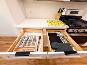 Una cocina con estufa, un mostrador con estampado de limón y dos cajones con utensilios.