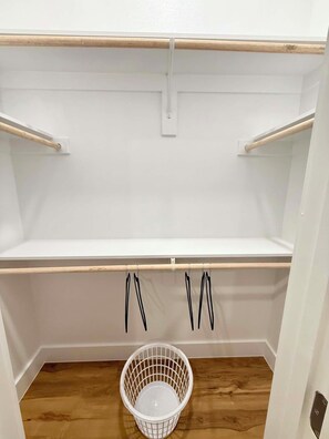 Un armario con estantes de madera, una cesta blanca y suelo de madera.