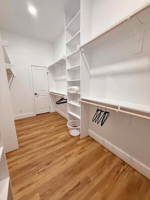 Ein begehbarer Kleiderschrank mit Holzboden, weißen Wänden und einer Tür.