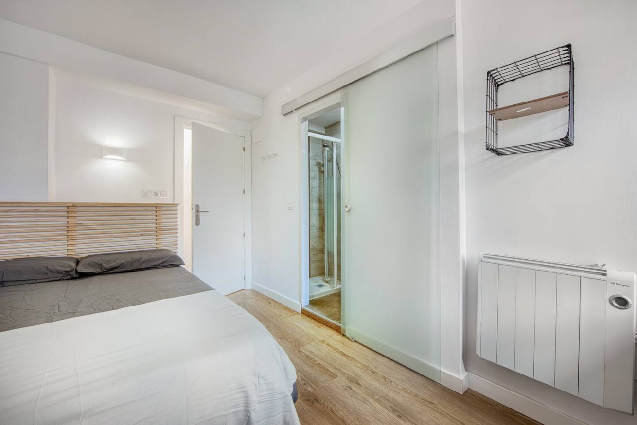 A bedroom with a bed, a bedside table, a wardrobe, and a radiator.
