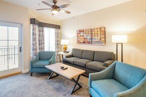 Ein Hotelzimmer mit einer Couch, zwei Sesseln, einem Couchtisch, einem Deckenventilator, einem Gemälde und einer Lampe.