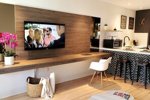 A modern kitchen with a flat-screen TV mounted on the wall, a bar area with stools, and a dining table. - Casa Cuba in Little Havana Brickell Free Parking (Miami)