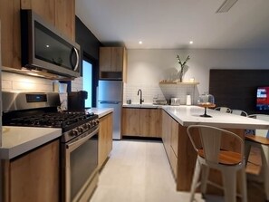 A modern kitchen with a built-in oven, microwave, and a large island with seating. - Casa Cuba in Little Havana Brickell Free Parking (Miami)