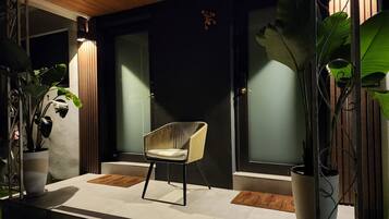 Una entrada moderna con una silla, plantas en macetas y un techo de madera.