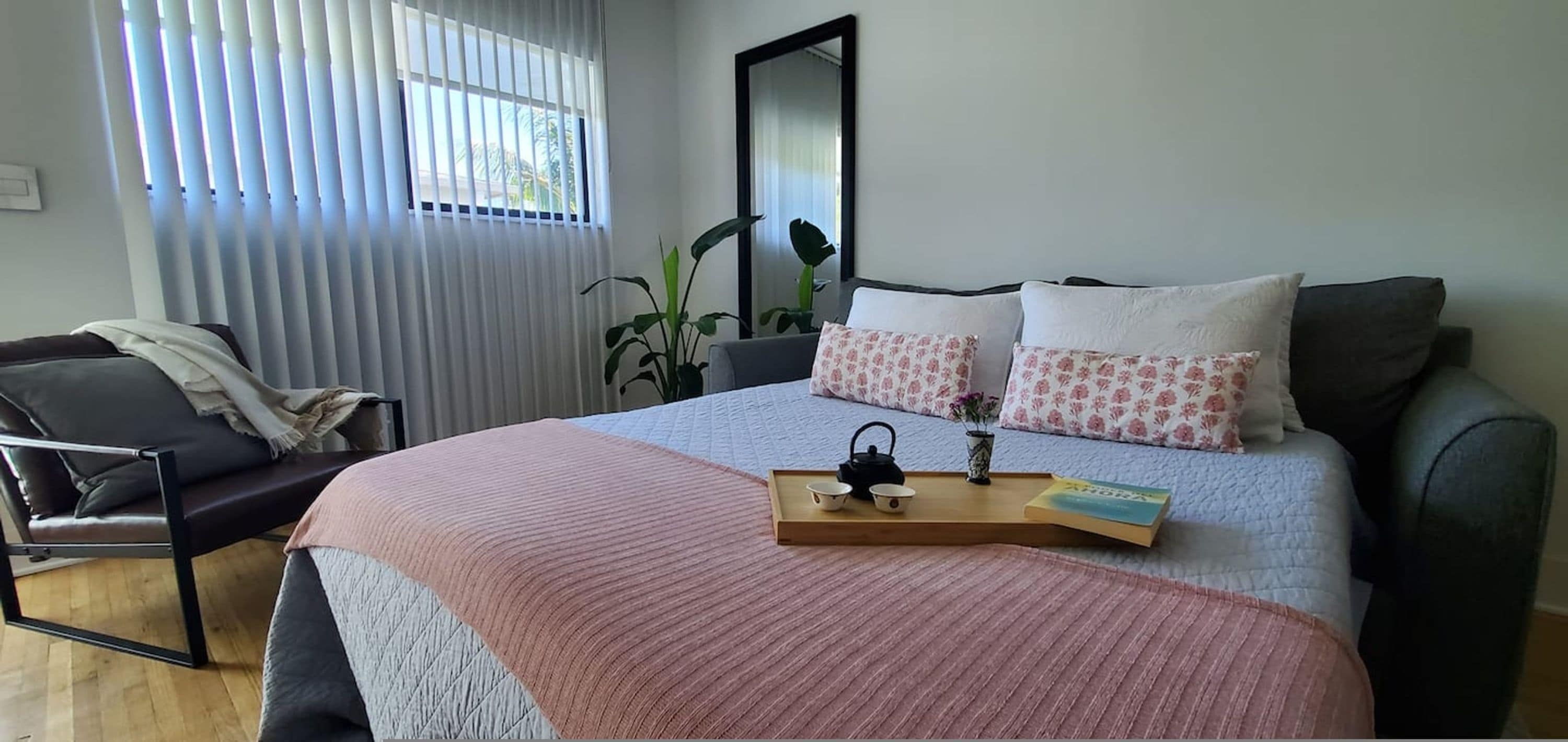Un dormitorio con cama, mesita de noche, silla y ventana con persianas.