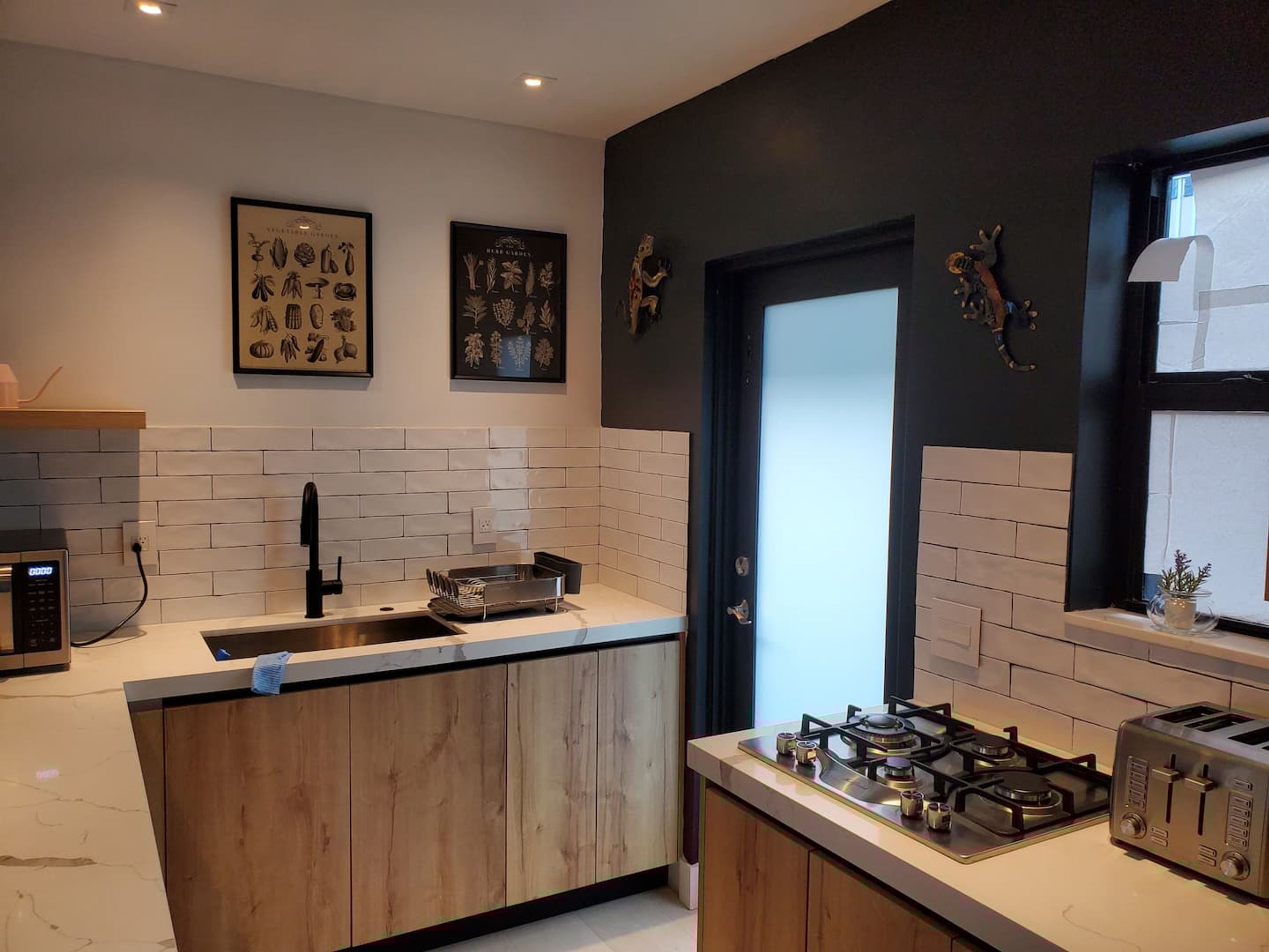 A modern kitchen with a central island, a gas stove, a toaster, and decorative wall art.