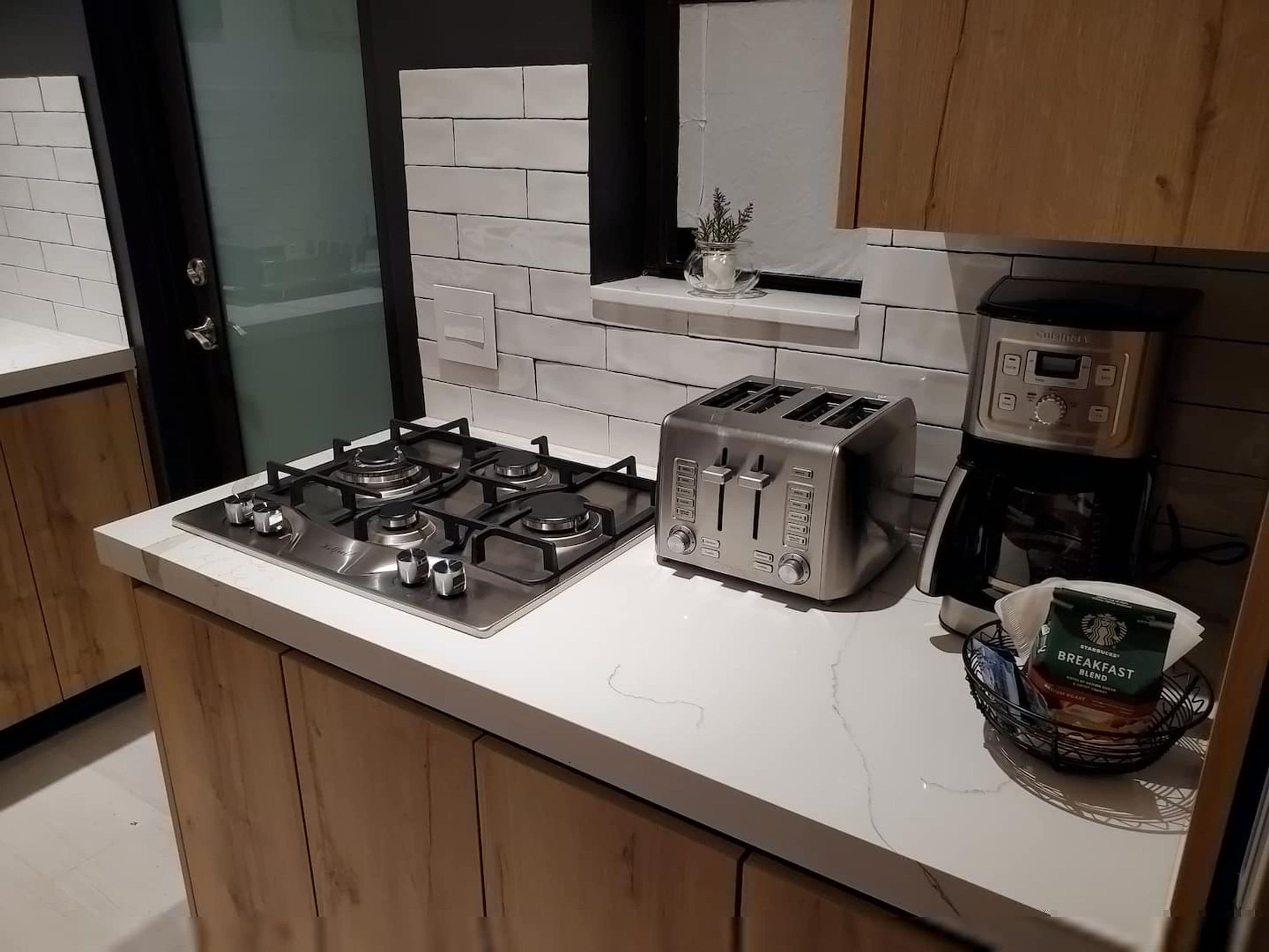 Een moderne keuken met een gasfornuis, een broodrooster en een koffiezetapparaat.