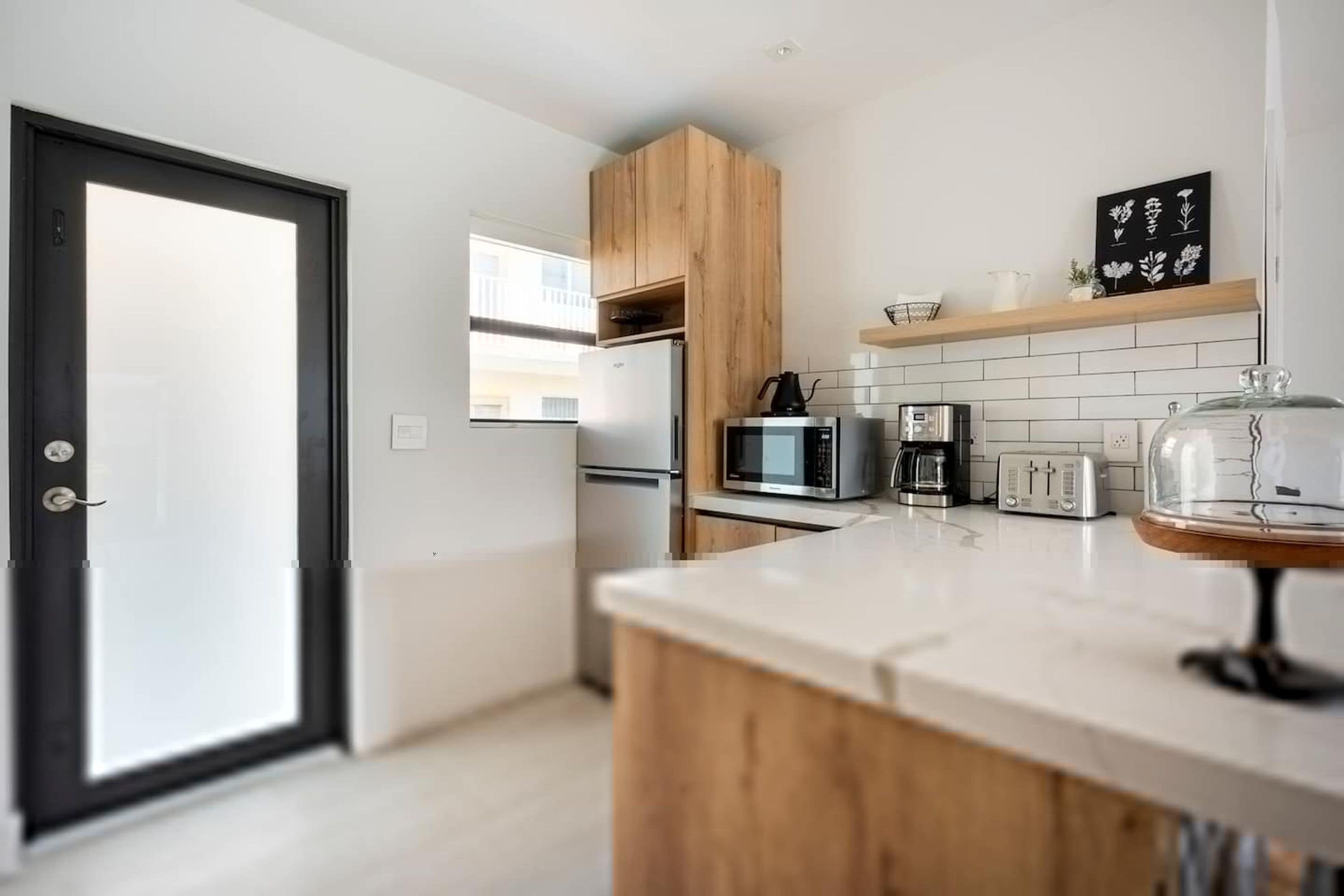 A modern kitchen with a refrigerator, microwave, coffee maker, and toaster.