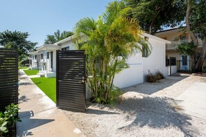 Zona residencial con un edificio blanco, un portón negro y una palmera.