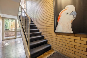 A staircase with a black carpet, a metal railing, and a brick wall. - Raleigh Escape Urban Comfort near Albert Park Lake (Windsor)