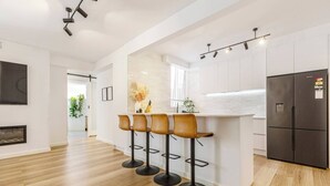 Een moderne keuken met een bar, houten vloeren en een geïntegreerde koelkast.