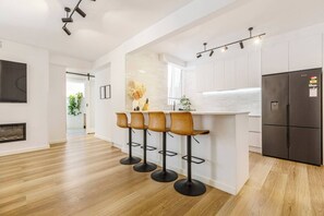 A modern kitchen with a bar area, wooden flooring, and a built-in refrigerator. - Raleigh Escape Urban Comfort near Albert Park Lake (Windsor)
