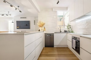 A modern kitchen with white cabinetry, a built-in dishwasher, and a stainless steel oven. - Raleigh Escape Urban Comfort near Albert Park Lake (Windsor)