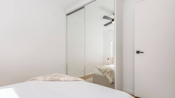 Een slaapkamer met een bed, een kledingkast en een deur.