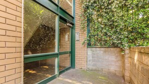 Een gebouw ingang met een glazen deur, bakstenen muren en een groen metalen omlijsting.