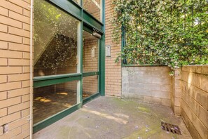 A building entrance with a glass door, brick walls, and a green metal frame. - Raleigh Escape Urban Comfort near Albert Park Lake (Windsor)