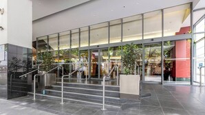 A modern building entrance with glass doors, a staircase, and metal railings. - Yarra Edge River and Skyline Views with Shared Pool (Melbourne)