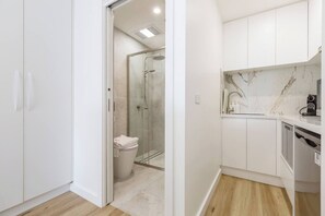 Une salle de bain moderne avec une douche à parois de verre, des toilettes et un lavabo doté d’un plan de travail en marbre.