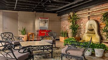 A cozy indoor seating area with a brick wall, a popcorn machine, and potted plants.