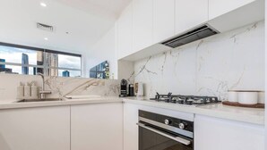 Uma cozinha moderna com armários brancos, painel de fundo de mármore, fogão a gás e forno.