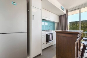 A compact kitchen with a refrigerator, oven, and sink.